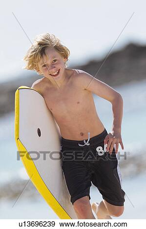 Boy carrying surfboard on beach View Large Photo Image Stock Photo - Boy carrying surfboard on beach. Fotosearch