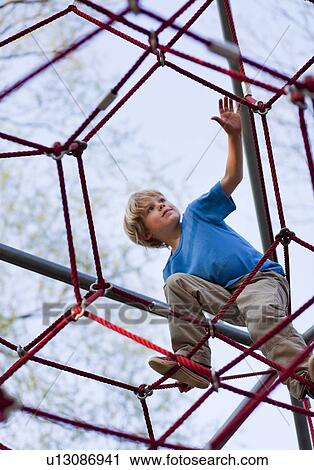 Stock Image - Boy climbing at playground. Fotosearch