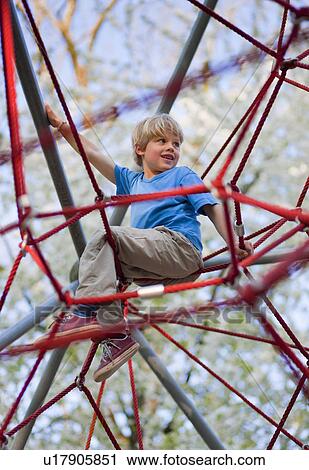 Stock Image - Boy climbing at playground. Fotosearch