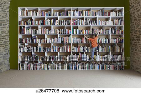 Stock Photo - Boy climbing bookshelves. Fotosearch