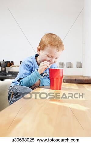 Boy drinking from straw in kitchen View Large Photo Image Stock Photography - Boy drinking from straw in kitchen. Fotosearch