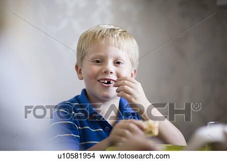 Boy eating at dinner table View Large Photo Image Picture - Boy eating at dinner table. Fotosearch