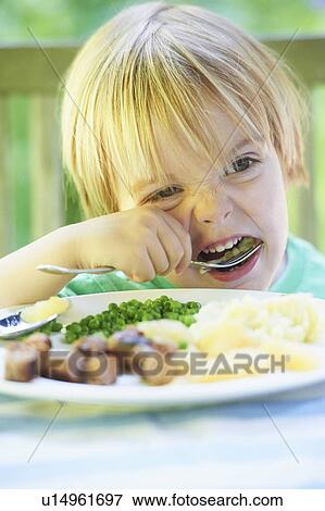 Stock Photo - Boy eating vegetables at dinner. Fotosearch