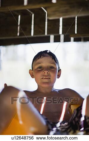 Stock Photograph - Boy floating under jetty on lake. Fotosearch