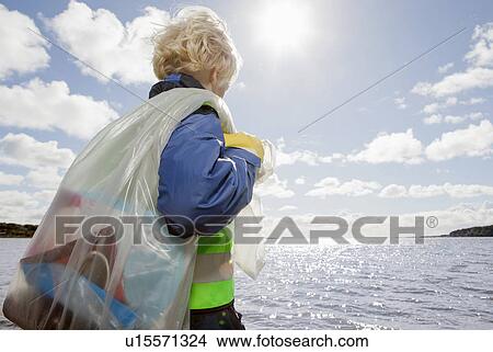 Boy hauling bag of trash on beach View Large Photo Image Picture - Boy hauling bag of trash on beach. Fotosearch
