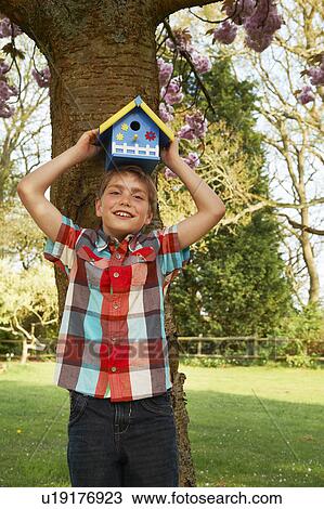 Boy holding birdhouse on his head View Large Photo Image Stock Image - Boy holding birdhouse on his head. Fotosearch