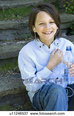 Boy in headphones holding water bottle View Large Photo Image Stock Photo - Boy in headphones holding water bottle . Fotosearch