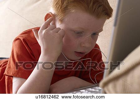 Boy in headphones using laptop on couch View Large Photo Image Stock Image - Boy in headphones using laptop on couch. Fotosearch