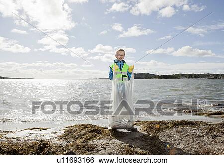 Stock Photograph - Boy in safety vest cleaning beach. Fotosearch