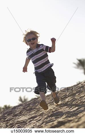 Stock Photography - Boy in sunglasses running on beach. Fotosearch