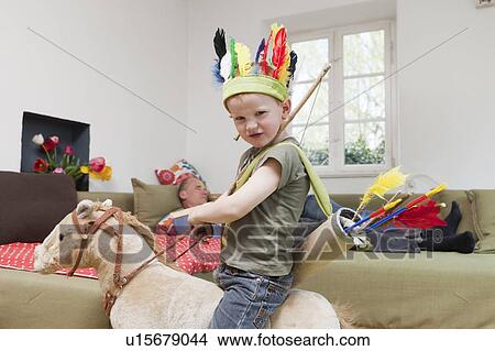 Picture - Boy in war bonnet playing with toys. Fotosearch