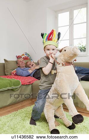 Stock Image - Boy in war bonnet playing with toys. Fotosearch