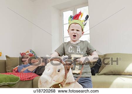 Boy in war bonnet playing with toys View Large Photo Image Stock Photo - Boy in war bonnet playing with toys. Fotosearch