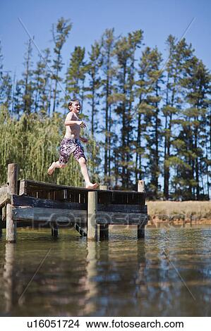 Picture - Boy jumping into lake from jetty. Fotosearch