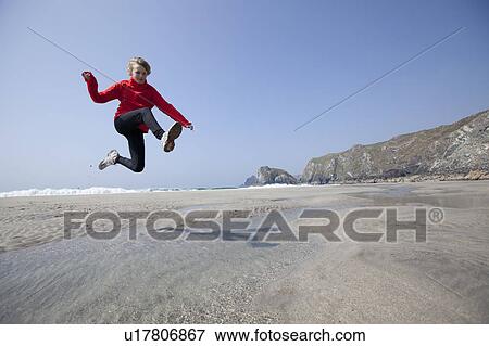 Stock Photo - Boy jumping over pools on beach. Fotosearch
