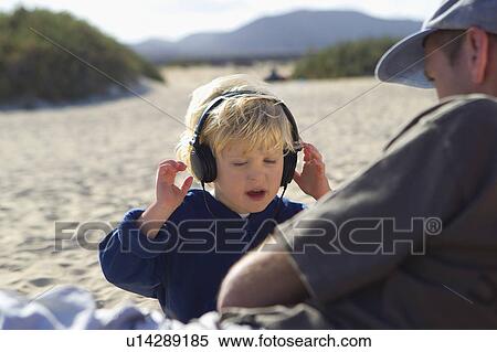Boy listening to headphones on beach View Large Photo Image Stock Photography - Boy listening to headphones on beach. Fotosearch