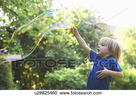 Boy making oversized bubble in backyard View Large Photo Image Stock Image - Boy making oversized bubble in backyard. Fotosearch