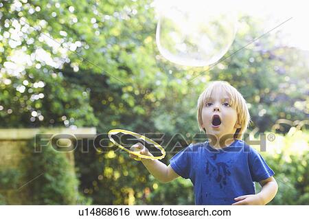 Stock Photograph - Boy making oversized bubble in backyard. Fotosearch