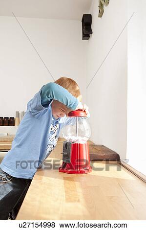 Boy opening gum ball machine in kitchen View Large Photo Image Stock Photo - Boy opening gum ball machine in kitchen. Fotosearch