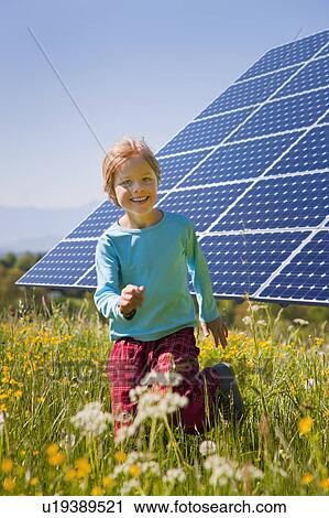 Stock Image - Boy playing in field by solar panel. Fotosearch