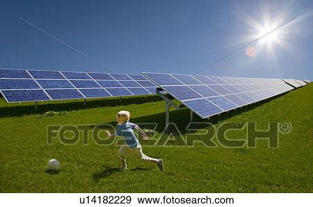 Boy playing in field by solar panels View Large Photo Image Stock Photo - Boy playing in field by solar panels. Fotosearch