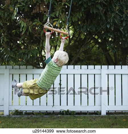 Stock Photo - Boy playing on swing in backyard. Fotosearch