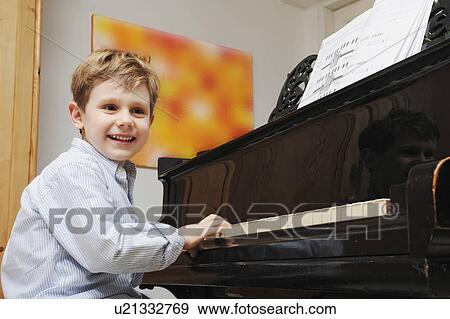 Stock Photo - Boy playing the piano in living room. Fotosearch