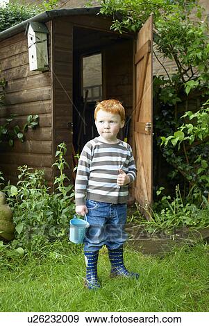 Boy playing with bucket in backyard View Large Photo Image Stock Photo - Boy playing with bucket in backyard. Fotosearch