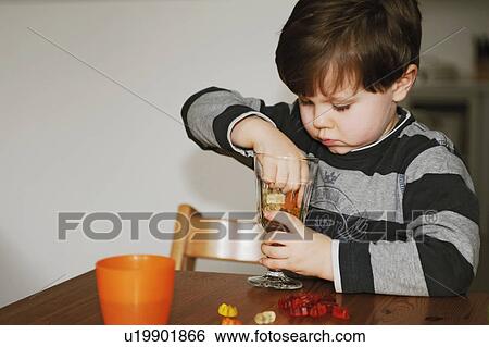 Stock Photograph - Boy playing with candy at table. Fotosearch