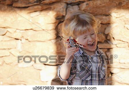 Stock Photo - Boy playing with toy airplane outdoors. Fotosearch