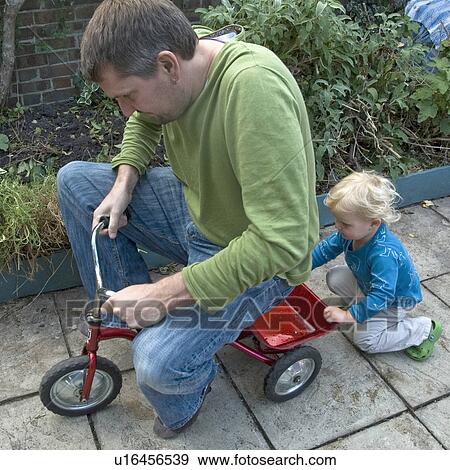 Stock Photo - Boy pushing father on tricycle. Fotosearch