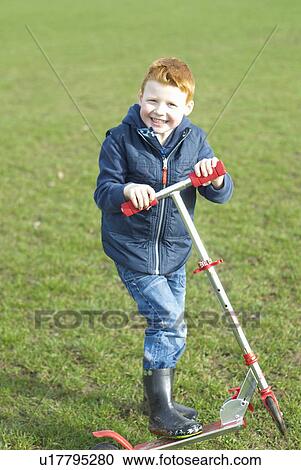 Boy riding scooter outdoors View Large Photo Image Stock Image - Boy riding scooter outdoors. Fotosearch