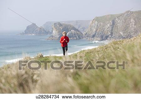 Picture - Boy running on cliffs over beach. Fotosearch