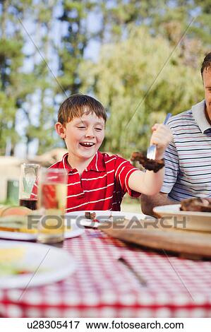 Boy serving himself meat at picnic table View Large Photo Image Stock Photo - Boy serving himself meat at picnic table. Fotosearch