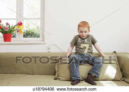 Boy sitting on sofa cushion View Large Photo Image Stock Photograph - Boy sitting on sofa cushion. Fotosearch