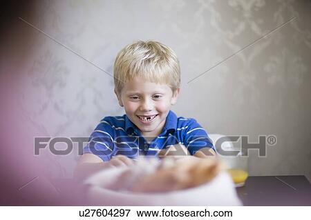 Stock Photo - Boy smiling at dinner table. Fotosearch