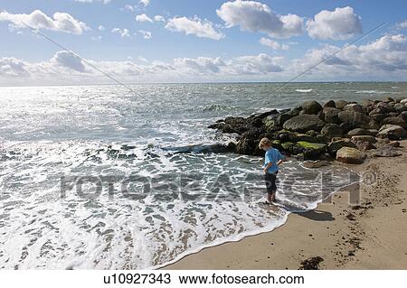 Boy standing in surf at the beach View Large Photo Image Stock Image - Boy standing in surf at the beach. Fotosearch