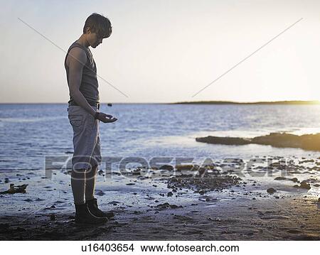 Picture - Boy tossing a pebble on beach. Fotosearch