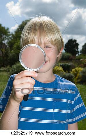 Stock Photo - Boy using magnifying glass outdoors. Fotosearch