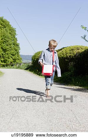 Stock Photo - Boy walking barefoot on rural road. Fotosearch