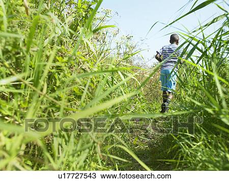 Boy walking in field of grass View Large Photo Image Stock Image - Boy walking in field of grass. Fotosearch