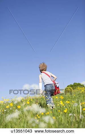 Boy walking through field of flowers View Large Photo Image Stock Image - Boy walking through field of flowers. Fotosearch