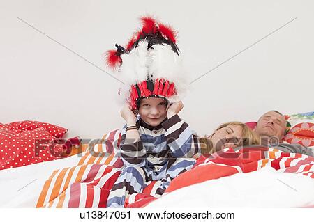 Boy wearing war bonnet in parents’ bed View Large Photo Image Stock Image - Boy wearing war bonnet in parents’ bed. Fotosearch