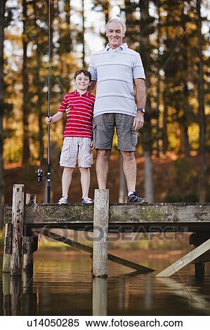 Stock Photography - Boy with grandfather on jetty over lake. Fotosearch
