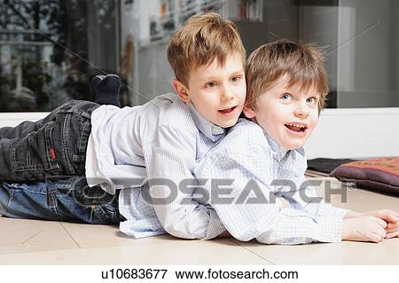 Stock Photo - Boys hugging on living room floor. Fotosearch