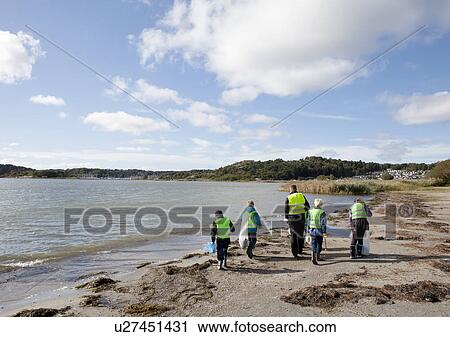 Stock Image - Boys in safety vests cleaning beach. Fotosearch