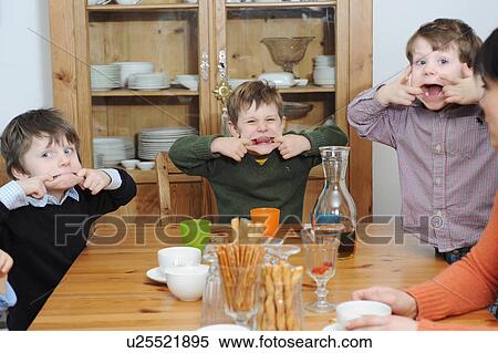 Stock Photography - Boys making faces at table. Fotosearch
