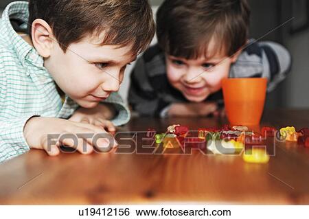 Stock Photograph - Boys playing with candy at table. Fotosearch