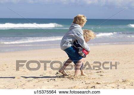 Picture - Boys playing with red ball on beach. Fotosearch