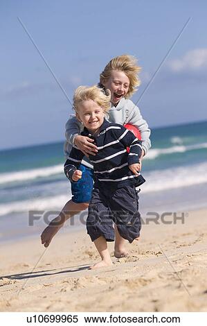 Stock Photography - Boys playing with red ball on beach. Fotosearch
